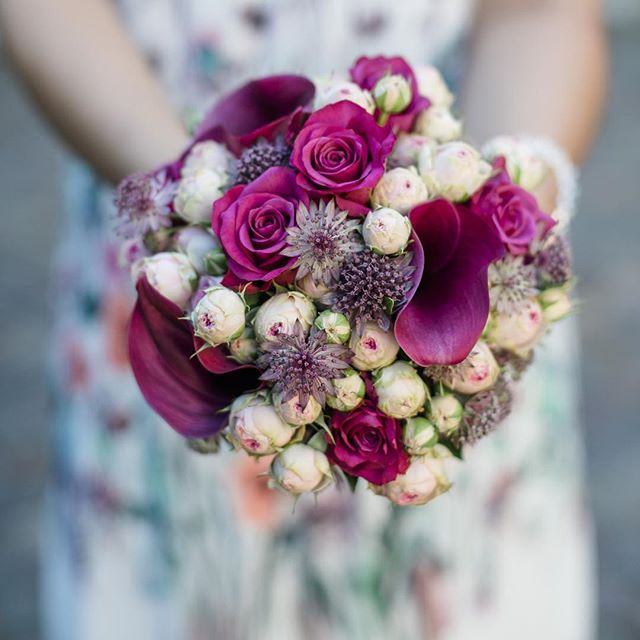 Close-up of a romantic wedding bouquet with roses and calla lilies in purple, white and green.