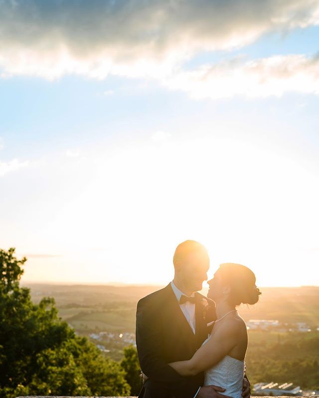 A bride and groom embrace at sunset, capturing a romantic moment during their wedding day.