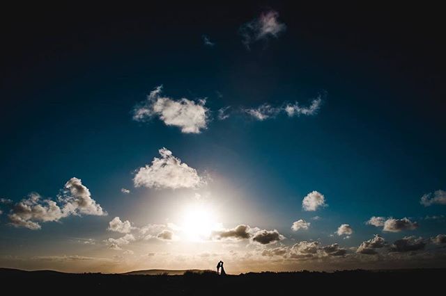 A couple silhouette kissing against a vibrant sunset sky, evoking romance and dreams.