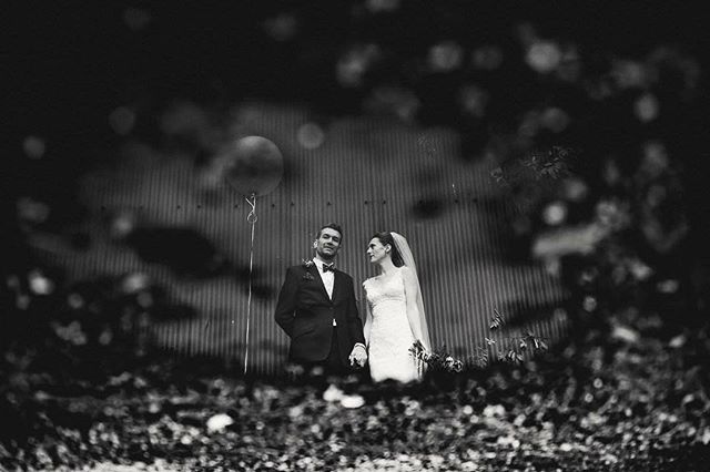 A newlywed couple poses in a black and white wedding photo, captured with a shallow depth of field and soft focus.