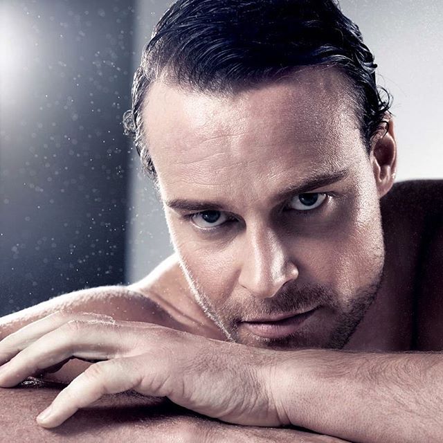 A handsome athlete poses for a portrait, showcasing a confident and intense gaze with a cool toned aesthetic.