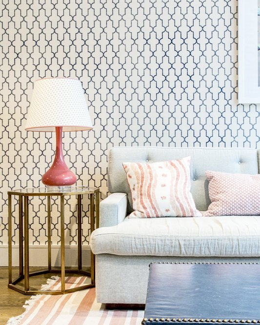 A serene living room featuring a stylish couch, lamp, and wallpaper creating a calm atmosphere.