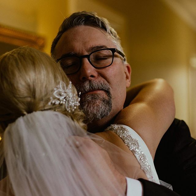 A tender moment between a father and his bride daughter during an indoor wedding celebration.