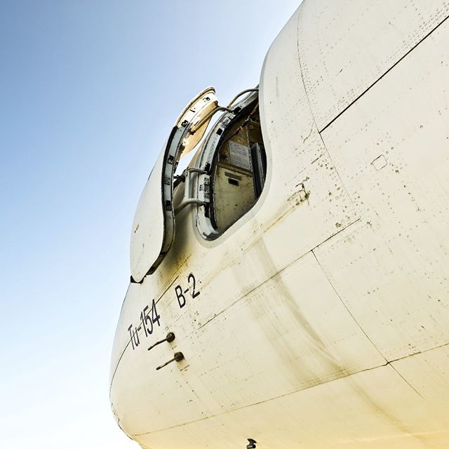 Close-up of an airplane with an open door under a blue sky. The aircraft is a Tupolev Tu-154.