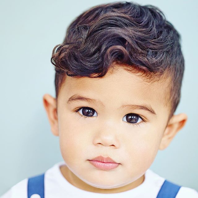 A charming portrait of a young boy with curly hair, looking directly at the camera with a sweet expression.