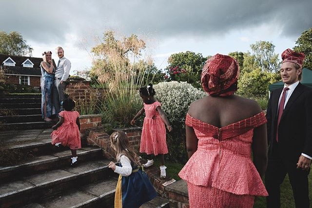 Guests gather at a wedding on brick stairs in a garden setting, creating a cheerful and celebratory atmosphere.