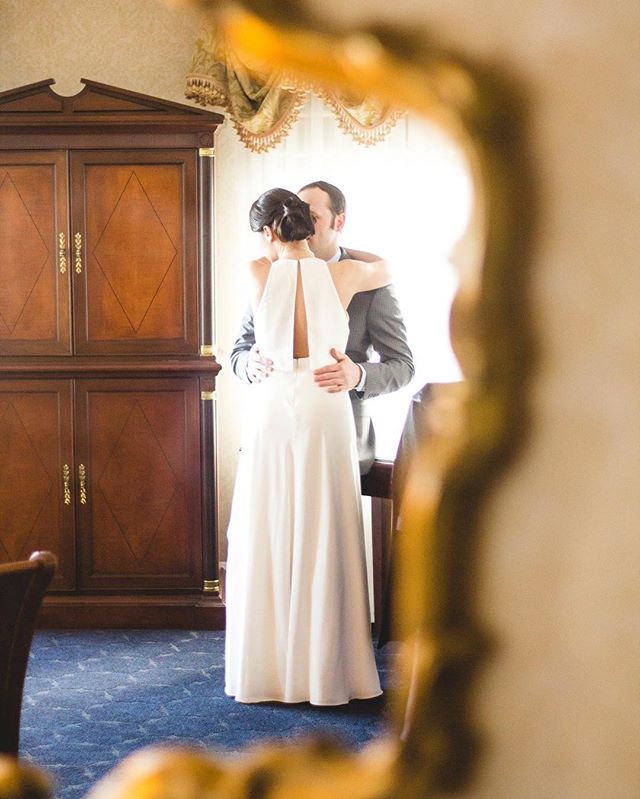 A bride and groom embrace tenderly in a hotel room, reflecting love and elegance.