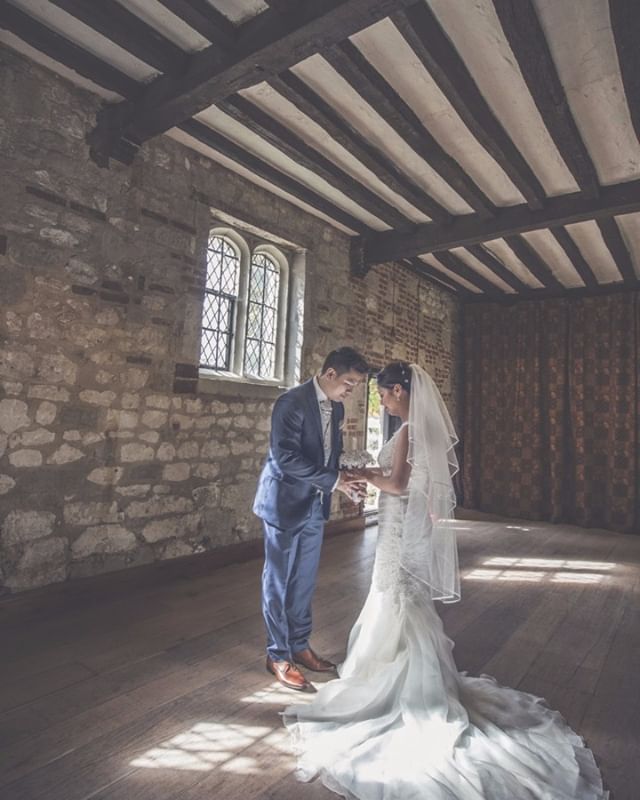 A bride and groom exchange rings at their wedding in a rustic, historic castle setting. 