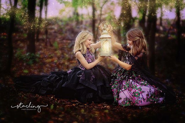 Two girls hold a glowing lantern in a mystical forest setting.