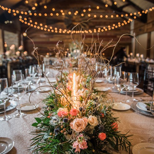 A beautifully decorated wedding table with floral centerpiece and candles creates a warm and romantic atmosphere.