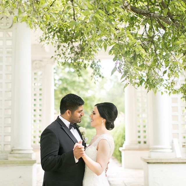 A bride and groom share an intimate moment in a lush garden on their wedding day.