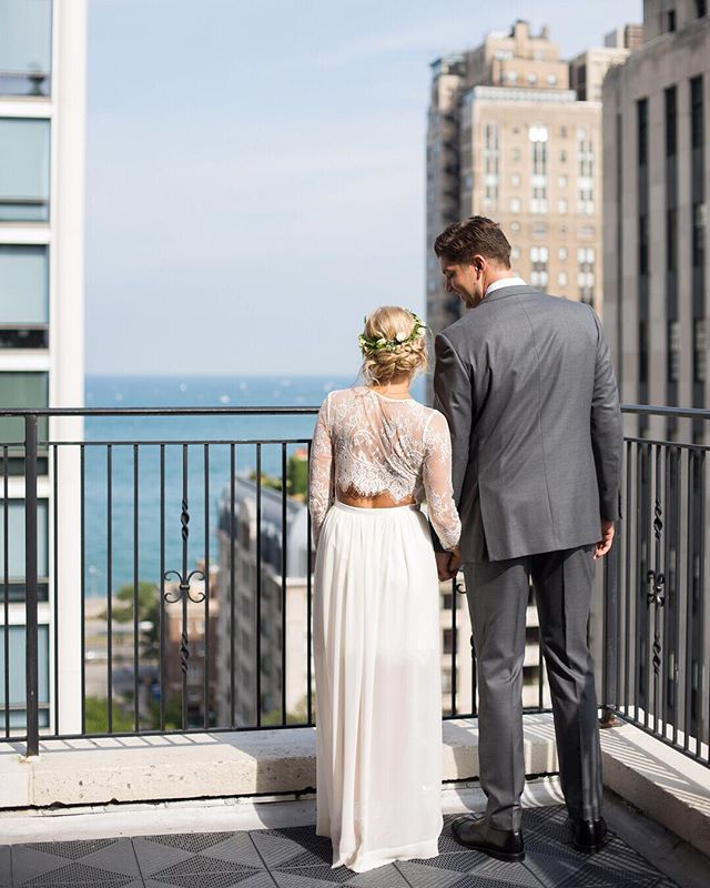A bride and groom hold hands on a rooftop with city views during their wedding.