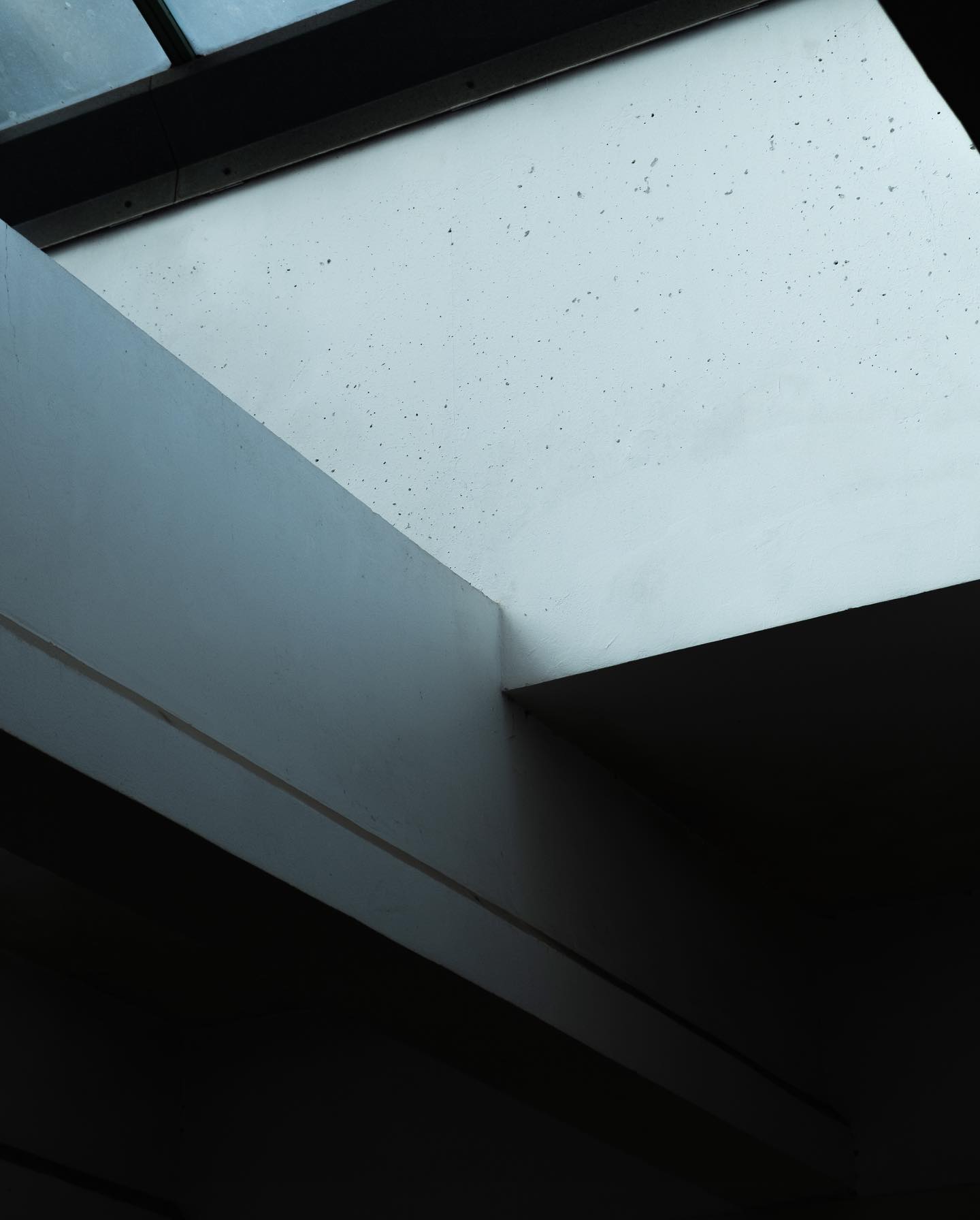 Abstract architectural detail featuring intersecting planes and contrasts of light and shadow.