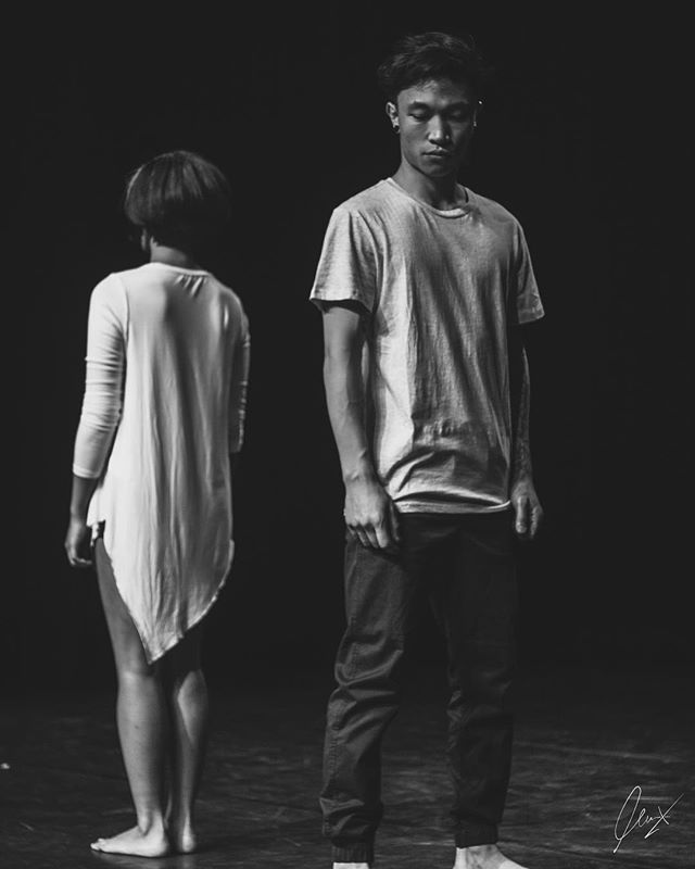 A man and a woman stand in minimalist pose, illuminated by soft lighting, perfect for performance art or emotional concepts.