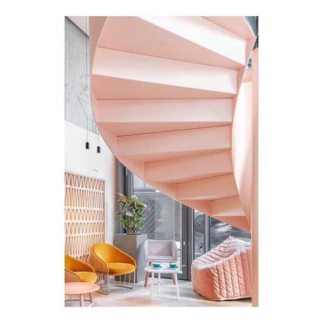 Stylish indoor space with a pink spiral staircase, armchairs, and a bean bag for a relaxing and modern atmosphere.