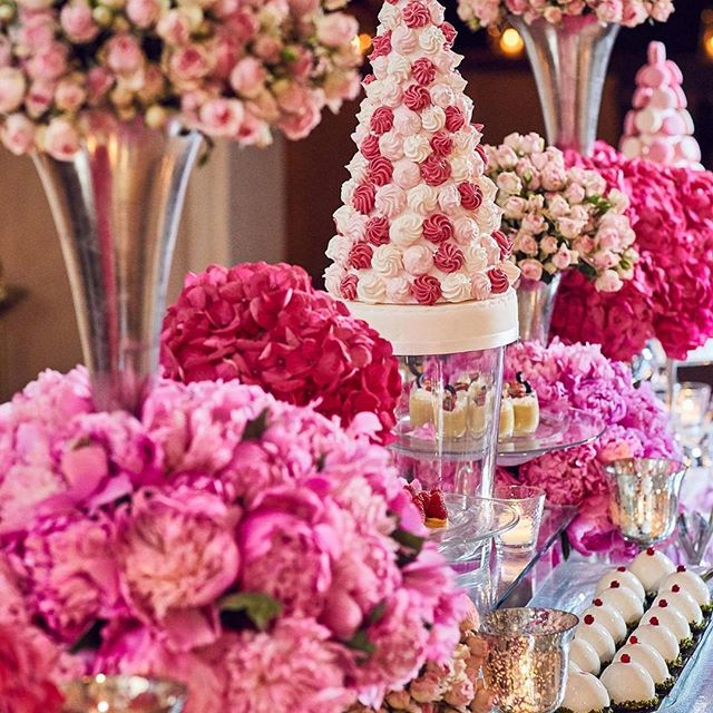 An elegant dessert table decorated with pink flowers and meringue cake creates a festive atmosphere.