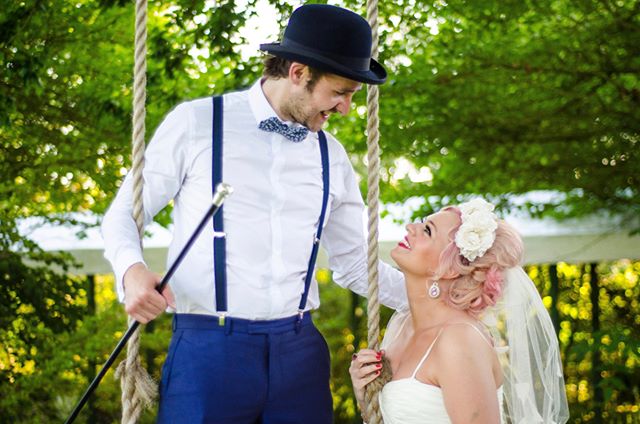 A bride and groom share a loving glance on a swing in a garden, capturing a romantic wedding moment.