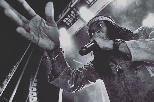A singer passionately performs on stage with a microphone, captured in a dynamic black and white shot.