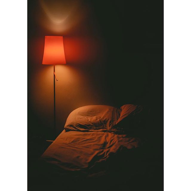 A cozy bedroom with a lamp illuminating a neatly made bed, creating a tranquil and inviting atmosphere for a restful night.