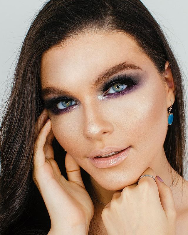 A stunning woman with glamorous makeup poses in a close-up studio shot.