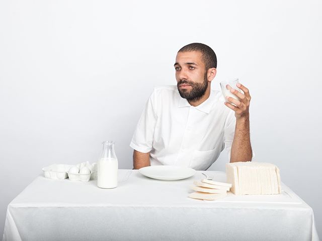 A man sits at a table with milk, bread, and eggs. Food concept for health and wellness, with a focus on a balanced diet.