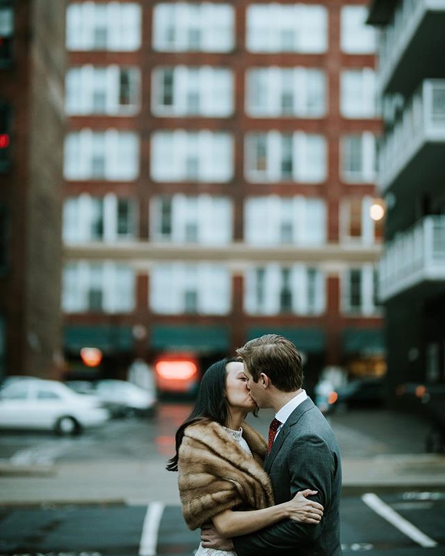 A couple shares an intimate kiss against an urban backdrop, radiating love and connection.