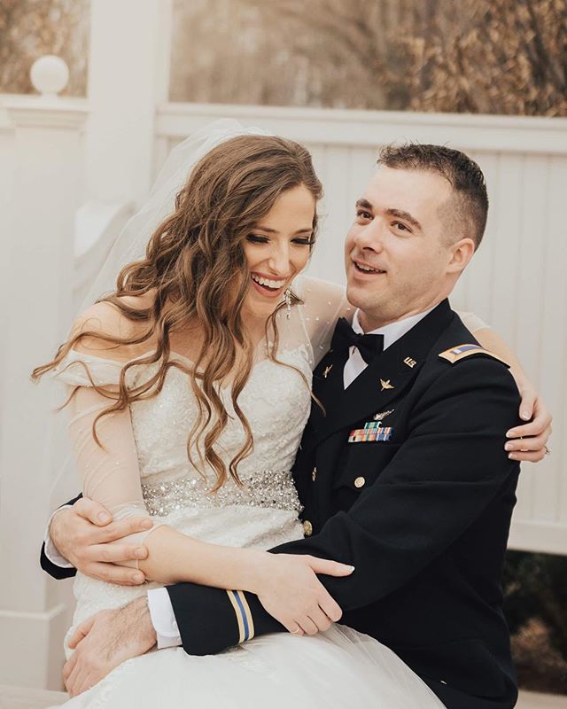 A happy military couple celebrates their wedding day with love and laughter outdoors.