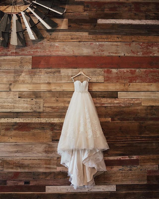 A beautiful wedding dress hanging on a rustic wooden wall, perfect for bridal fashion inspiration.