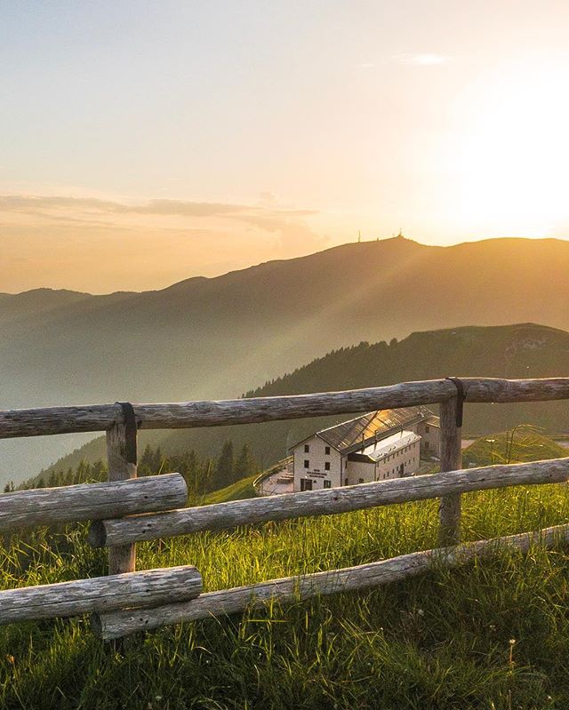A building nestled in a mountain landscape is framed by a rustic fence, evoking tranquility and natural beauty.