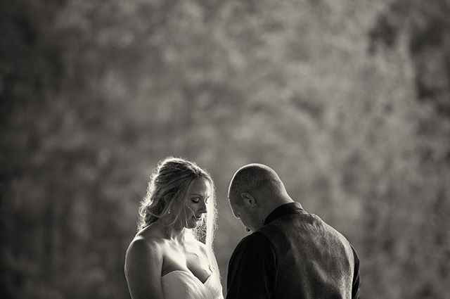 A bride and groom share an intimate moment in black and white during their wedding ceremony.
