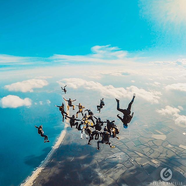 A group of skydivers perform a coordinated jump above the coastline. Aerial action shot perfect for adventure and sports marketing.
