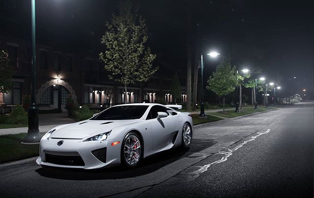 A sleek white Lexus LFA parked on a city street at night, illuminated by streetlights.