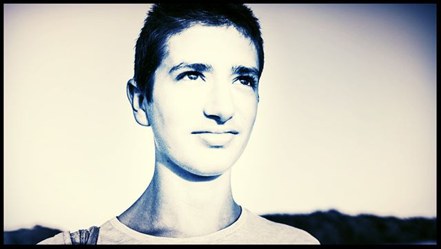 Portrait of a young man looking thoughtfully into the distance against a bright sky.