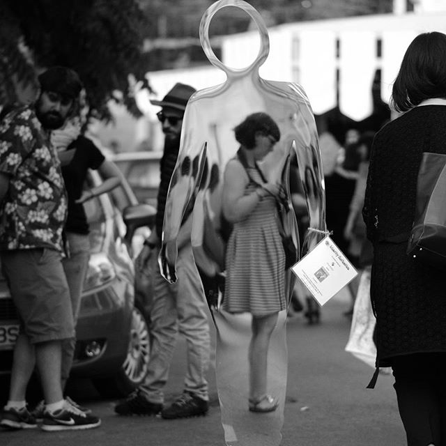 A monochrome street scene features people and a transparent mannequin creating a layered, artistic composition.