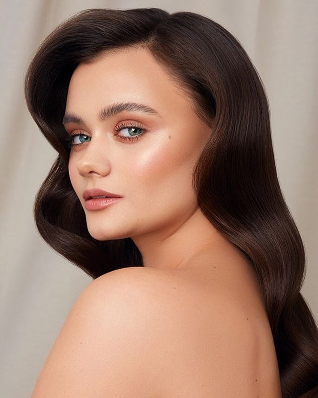 Elegant brunette model poses in soft light, perfect for beauty and skincare advertising.