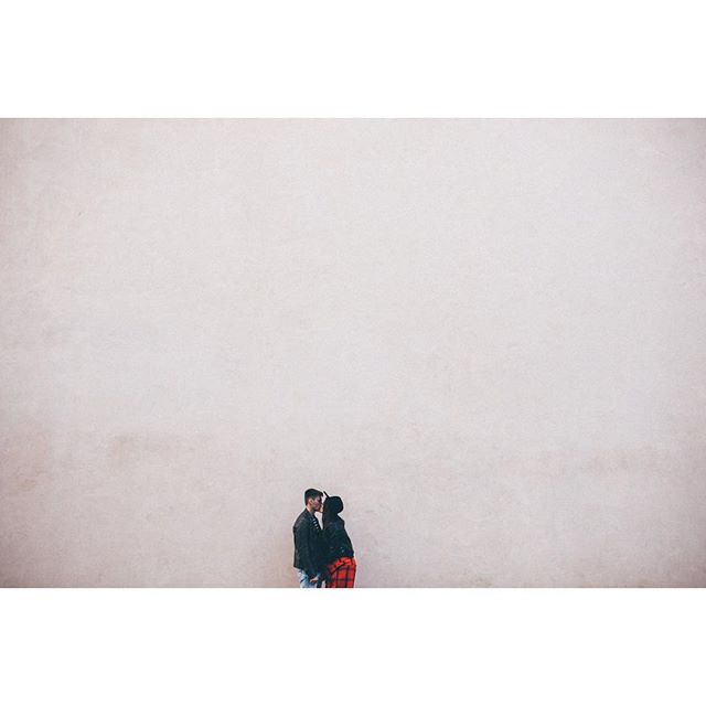 A couple embraces in a tender kiss against a neutral wall, perfect for romantic themes.
