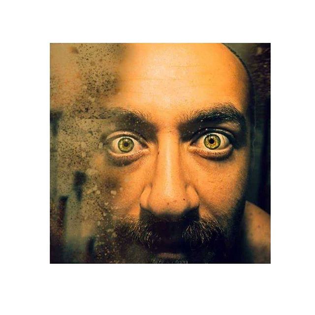 Close-up of a man's face with intense eyes, creating a moody and mysterious atmosphere in a self-portrait.