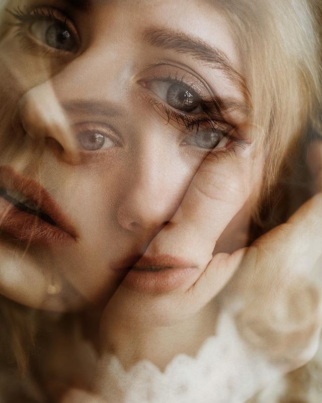 A woman's face is softly lit, with a hand gently touching her skin in an emotional and intimate portrait.