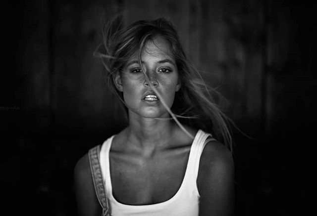 Monochrome portrait of a woman with windblown hair in a natural, emotional style, close up shot.