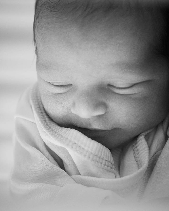 Close-up of a newborn baby sleeping peacefully. Soft light and black and white tones enhance the tender moment.