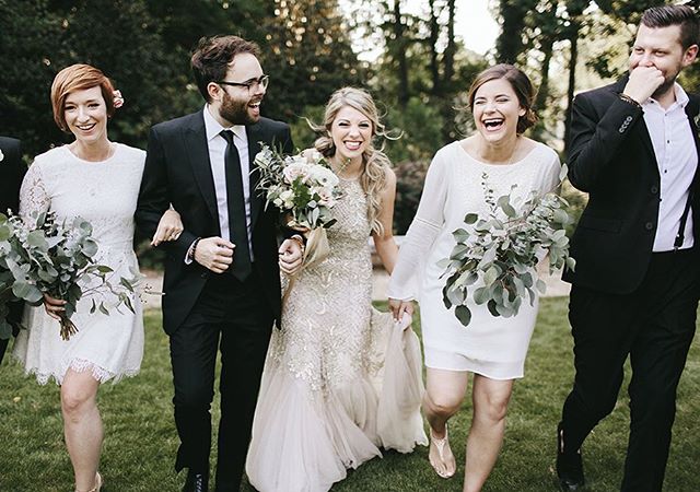 A joyous wedding party strolls through a lush garden, laughing and celebrating the newlyweds' special day.