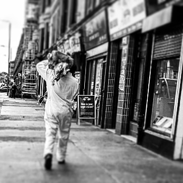 A person walks down a city sidewalk in a black and white street photography style image.