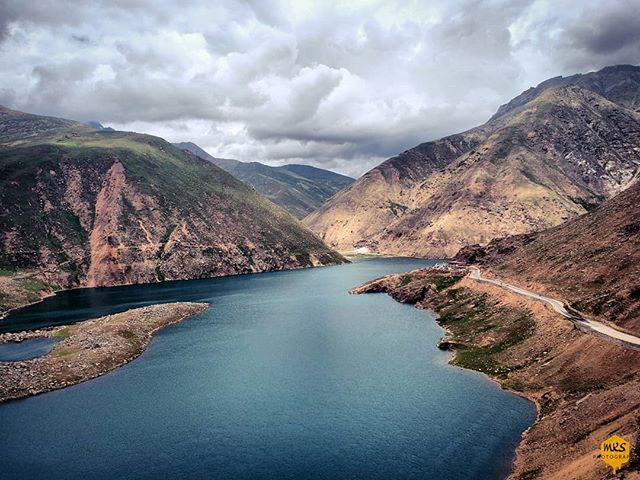Aerial view of a cityscape with a construction site and cranes under a cloudy sky.