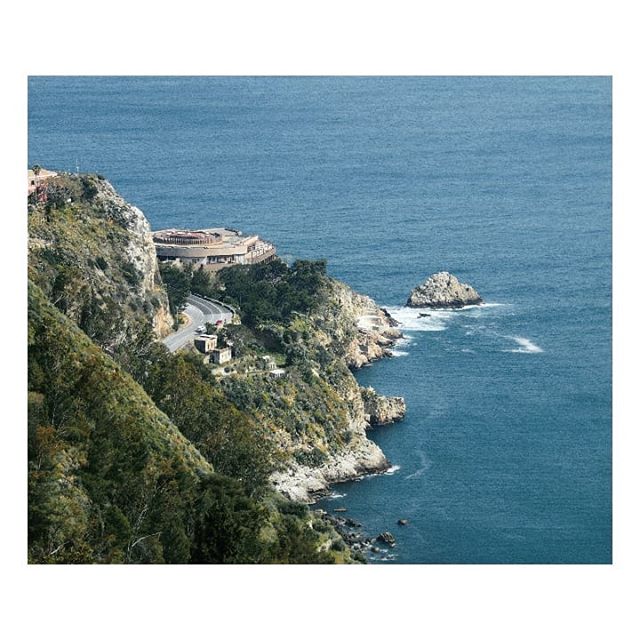 Scenic view of California's coastline featuring cliffs, the ocean, and a building on the edge.