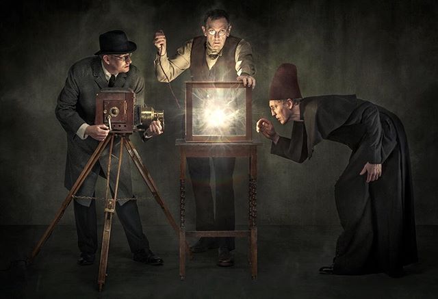 Three men in vintage attire engage with a mysterious glowing box, capturing a surreal, historic moment.