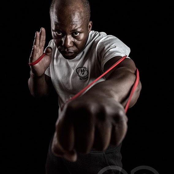 An athlete demonstrates strength and determination using resistance bands against a dark background.
