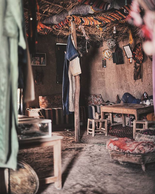 A cozy, rustic interior showcases a person relaxing in a warmly lit, vintage-style living room with earth tones.