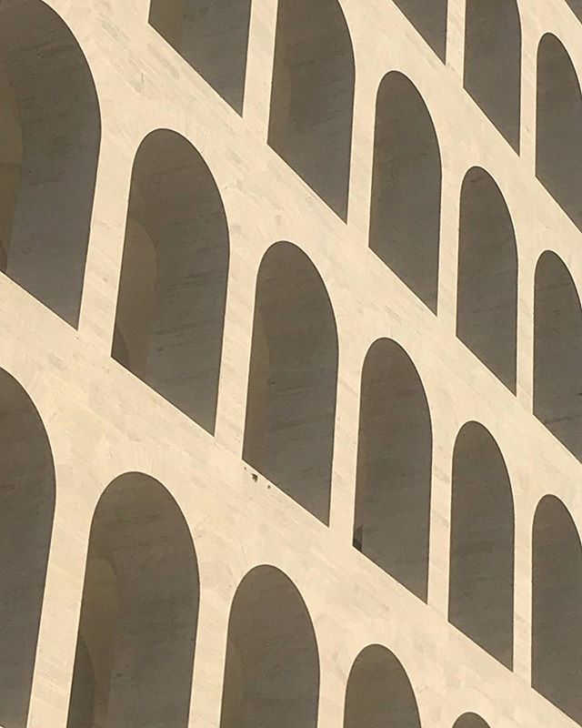 Abstract architectural view of a building facade featuring rows of rounded arches, creating a rhythmic geometric pattern.