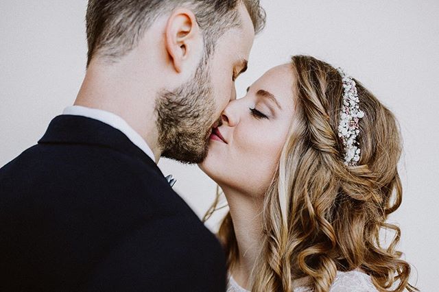 A bride and groom share an intimate kiss in a tender and romantic wedding moment, showcasing love and affection.
