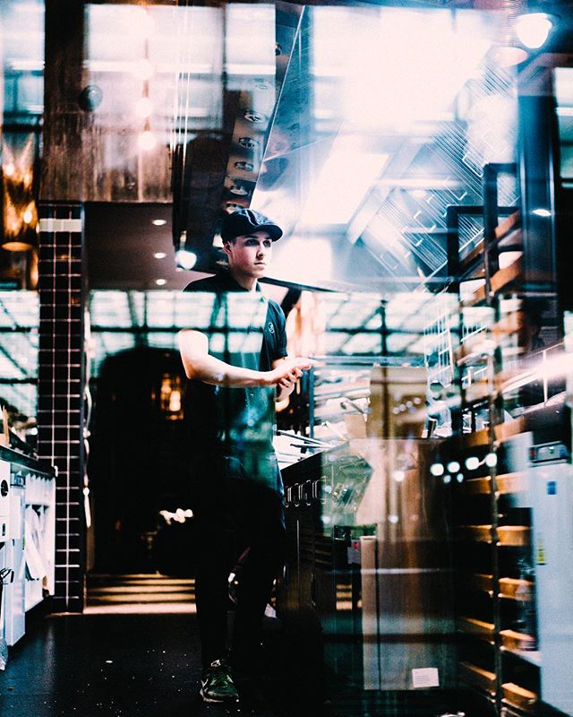 A chef stands in a professional kitchen, ready to prepare dishes for restaurant patrons.